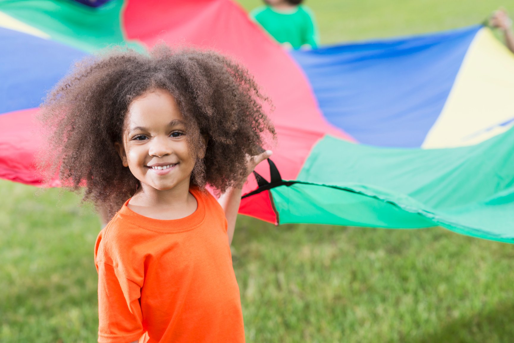 African American girl at summer camp holding parachute